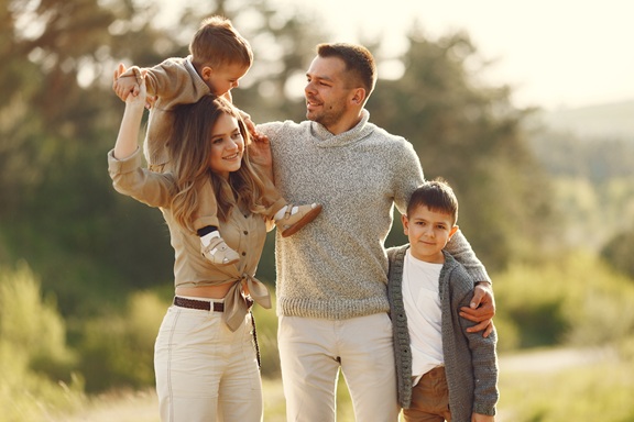 Family with cute little child. Father in a gray sweater. Sunset background.